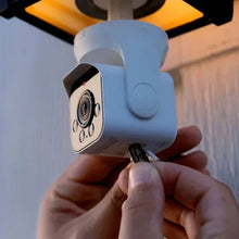 Bulb camera housing with lens and round button, shown during bulb installation