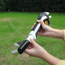 Hands holding cordless garden multi-tool with pruning attachment on handle