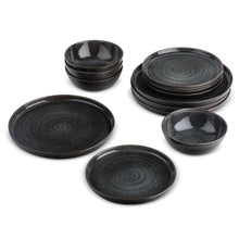 Black ceramic dinnerware set with bowls and plates, reactive glaze swirl pattern
