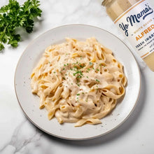 Creamy Alfredo pasta in a bowl with herbs, with Alfredo sauce jar