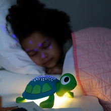 Green and blue turtle sound machine with glowing star dome near sleeping child