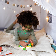 Green and blue turtle sound machine with star dome, used on a bed