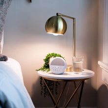 White round night sound machine with glowing light ring on bedside table