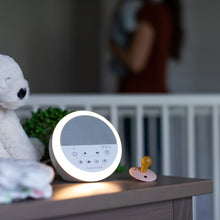 White round night sound machine with glowing light ring on a table