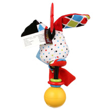 Dog-shaped fabric baby rattle with geometric wing, red strap, and yellow ball base
