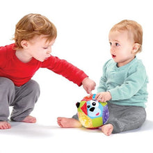 Colorful light-up plush ball with cow face, held during baby play
