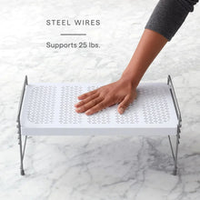 White wire mesh shelf with steel legs and a hand pressing the top surface