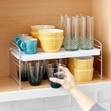 Adjustable white wire shelf unit with mesh top, stacked cups and bowls on two levels
