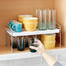 Two-tier white wire shelf organizer with stacked cups and bowls