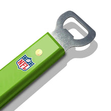 Green-handled BBQ tool with NFL shield patch and metal bottle-opener style end