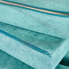 Teal-green foam cushion with blue zipper track along the seam