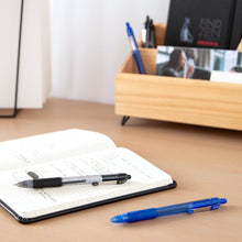 Retractable ballpoint pens, one black and one blue, on an open notebook