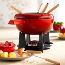 Red enamel-style fondue pot with wooden forks and black burner base
