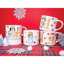 Ceramic holiday mug set on plaid fabric with snowy decorations and character prints