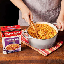 Family-size jambalaya dinner mix box beside a pot of cooked jambalaya in hands.