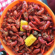 Crawfish and shrimp in an orange bowl with two pieces of corn