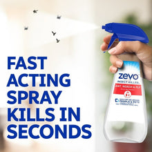 Hand holding insect killer spray bottle with blue trigger nozzle over floor