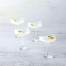 Set of coupe cocktail glasses with clear bowls and gold citrus garnish on each.