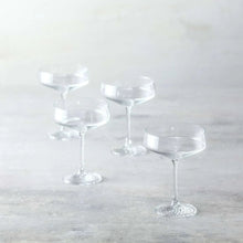 Set of coupe cocktail glasses, clear bowls and patterned foot on slender stems.