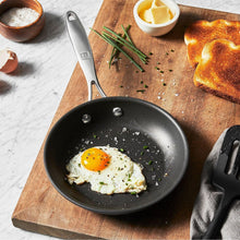 Non-stick black aluminum skillet with fried egg and speckled pepper