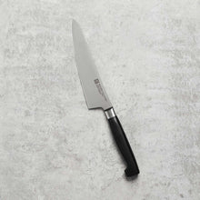 Stainless prep knife with black handle, straight blade angled on gray surface