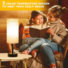 Bedside table lamp with linen shade and black base, softly lit for reading