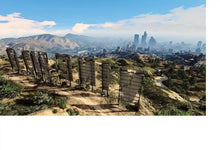 Wide city landscape view with mountains, hillside fence posts, and a distant skyline
