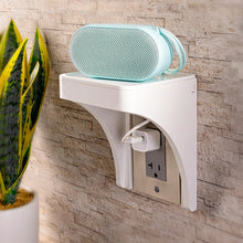 White outlet shelf mounted on wall with cord storage compartment and plugged outlet