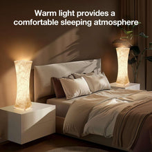 Fabric table lamp with tall textured white shade, warm light glowing