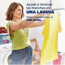 Person holding a yellow shirt for one-wash stain removal with laundry detergent