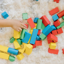 Hands sorting and building with colorful wooden blocks on a soft carpet.