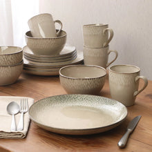 Grey stoneware dinnerware set on table, bowls, mugs and plates with cutlery
