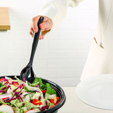 Black plastic serving spoon scooping salad from a bowl