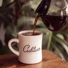 Cultivar coffee poured into a branded ceramic mug.