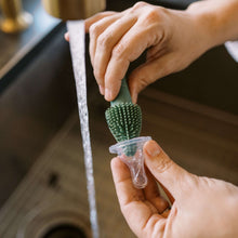 Silicone straw cleaning brush being used on a bottle opening, green bristle head