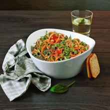 White wavy porcelain salad bowl with mixed vegetables, bread, and greens