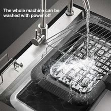 Electric smokeless grill being rinsed with water on the cooking plate and racks.