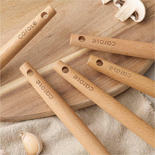 Wooden utensil handles with hanging holes, stacked on a cloth