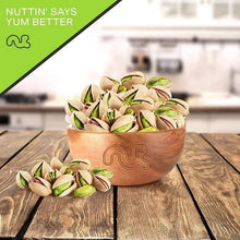 Roasted salted pistachios in a terracotta bowl with scattered in-shell nuts