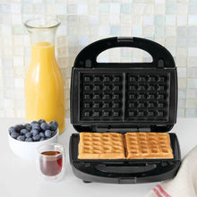 Black waffle and sandwich maker with waffle plates open, holding two golden waffles