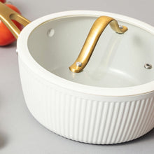 White ribbed saucepan with gold handle and matching interior rim detail