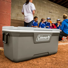 Coleman hard chest cooler on ground with side handles and front logo