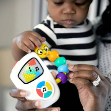 Close-up: hands holding musical take-along toy with colorful bead chaser and screen