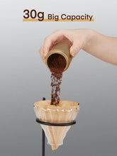 Manual coffee grinder pouring freshly ground coffee from the top into a filter cone