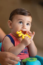 Yellow and blue teether pieces with baby holding the yellow part