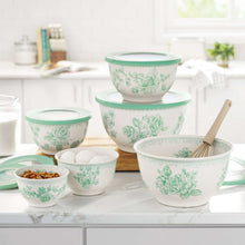 Green floral nesting mixing bowls and lids arranged on kitchen counter