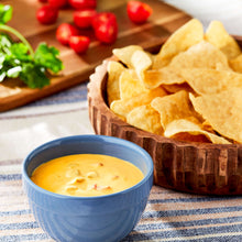 Salsa con queso cheese dip in blue bowl with tortilla chips and red toppings