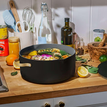 Black ceramic nonstick stock pot with strainer lid, filled with prepared food