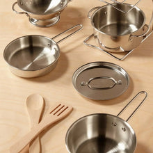 Assorted stainless steel pots and pans with lids and wooden utensils on tabletop