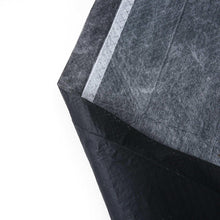 Folded dark charcoal training pad with light white stripe and layered absorbent edge.